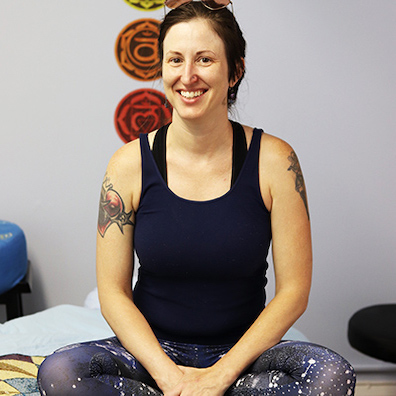 Image of Jamie Szuta sitting on a massage table in her office